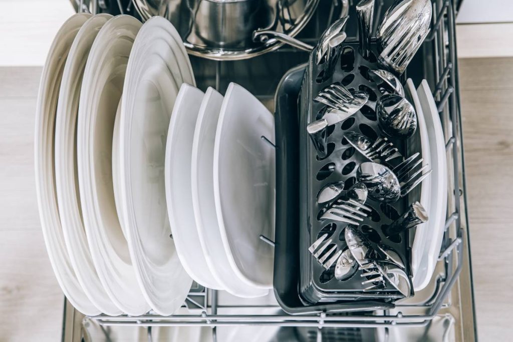 Open dishwasher with clean dishes close-up after washing. Clean utensil in open dishwashing machine.