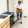 Repair of dishwashers. Repairman repairing dishwasher in kitchen.