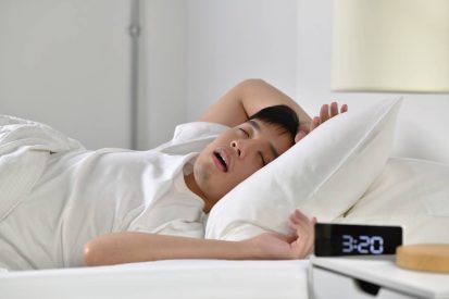 Young Asian man sleeping and snoring loudly lying in the bed
