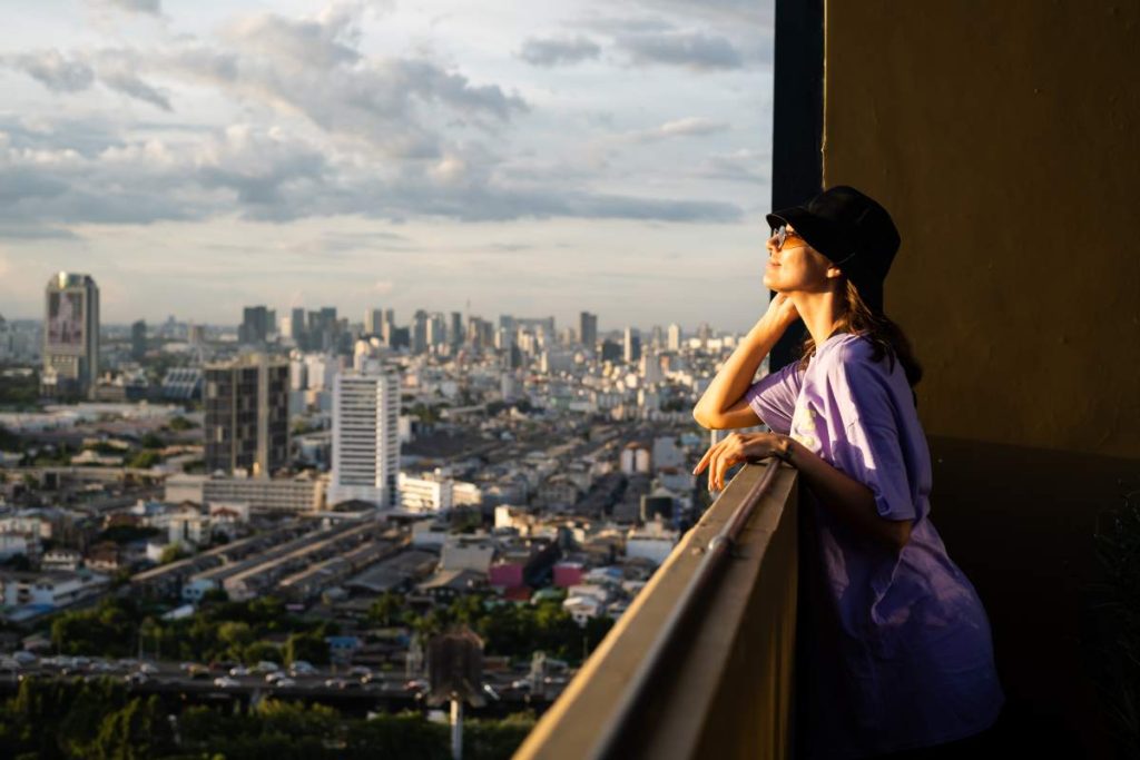 caucasian woman in trendy panama and waist neon bag on roof