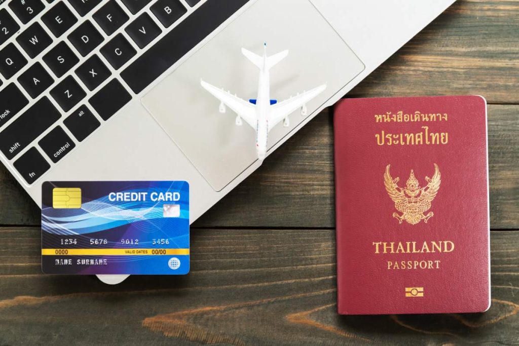 Passport with  credit card on laptop keyboard on a brown wooden background, Preparation for Traveling concept