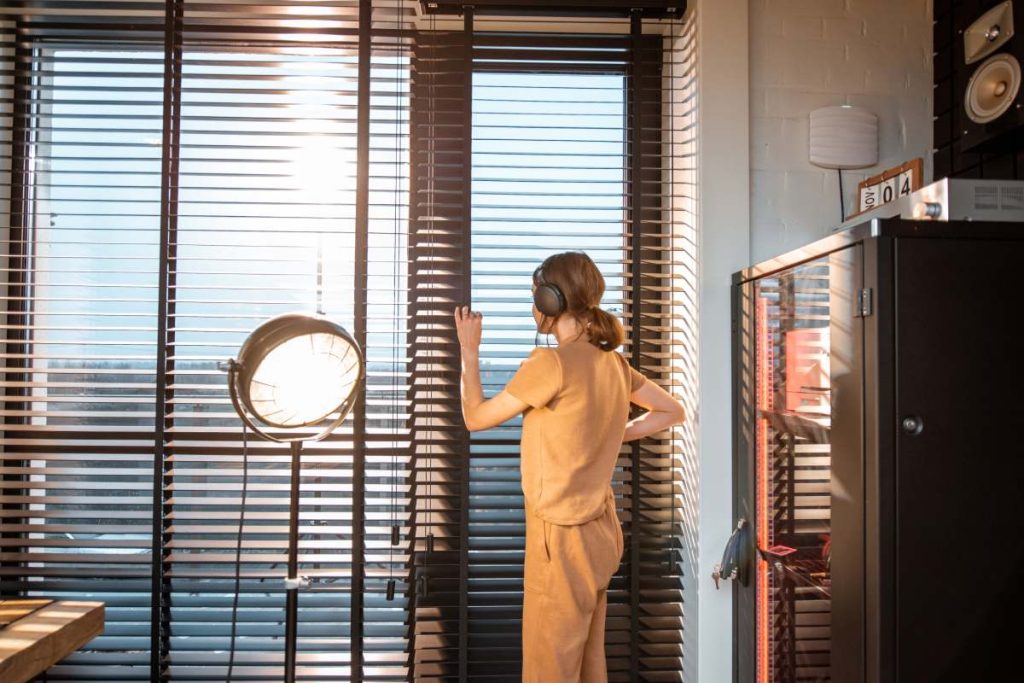 Young woman in domestic suit looks out the window of her modern home studio. Concept of quarantine and work from home