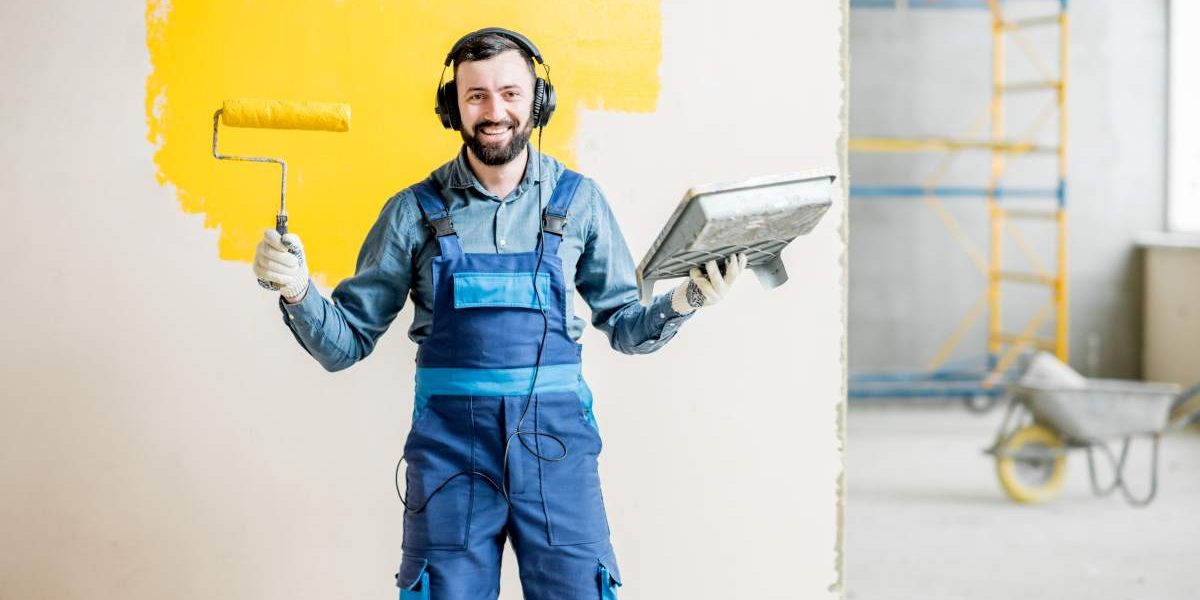 Portrait of a happy repairman listening to the music with headphones during the painting process indoors