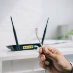 cropped view of businessman holding wire with connector near router