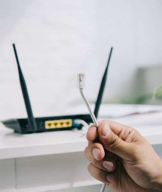 cropped view of businessman holding wire with connector near router