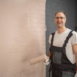 Man Painting Brick Wall in Overalls