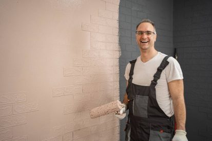 Man Painting Brick Wall in Overalls