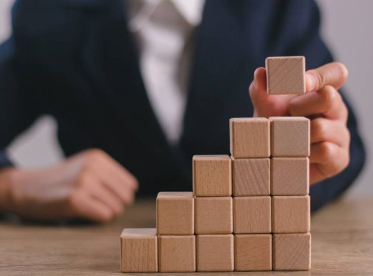 Businesswomen stack blank wooden cubes on the table with copy space, empty wooden cubes for input wording, and an infographic icon.