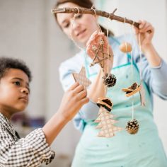 Cute boy holding paper star decoration hanging on stick among other toys
