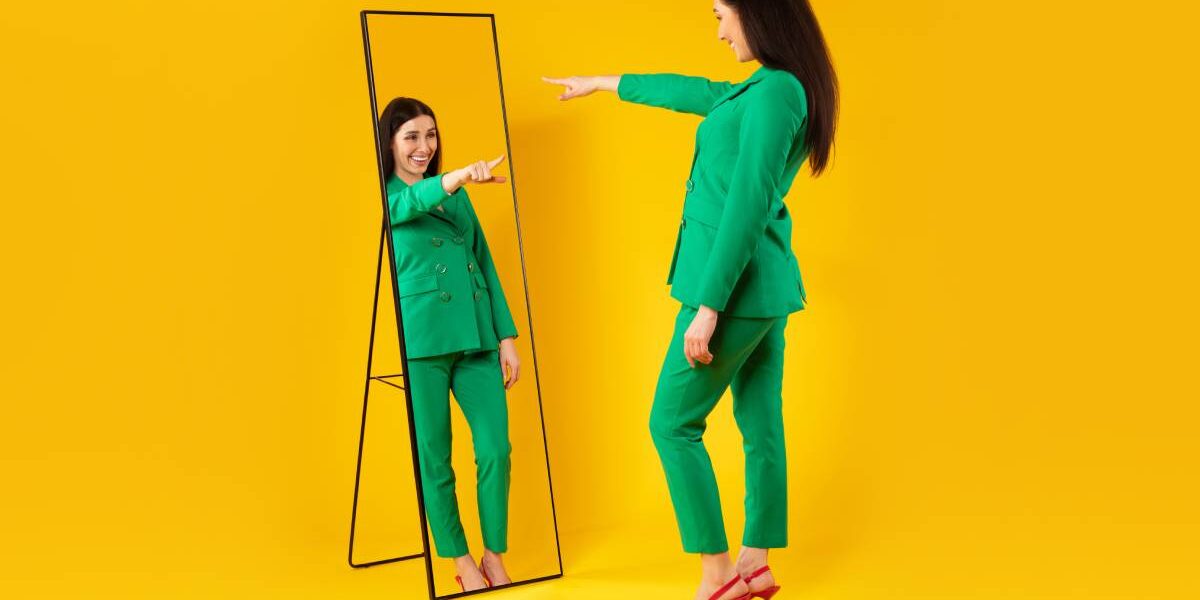 I choose myself. Excited stylish lady pointing finger at her reflection in mirror, yellow background, free space
