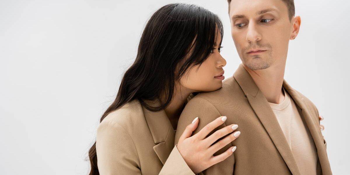 Losing a Partner asian woman with long brunette hair hugging man in beige jacket isolated on grey