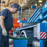 Profile photo of serious man that bowing his head while looking at case with instrument, being in workshop