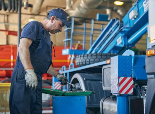 Profile photo of serious man that bowing his head while looking at case with instrument, being in workshop